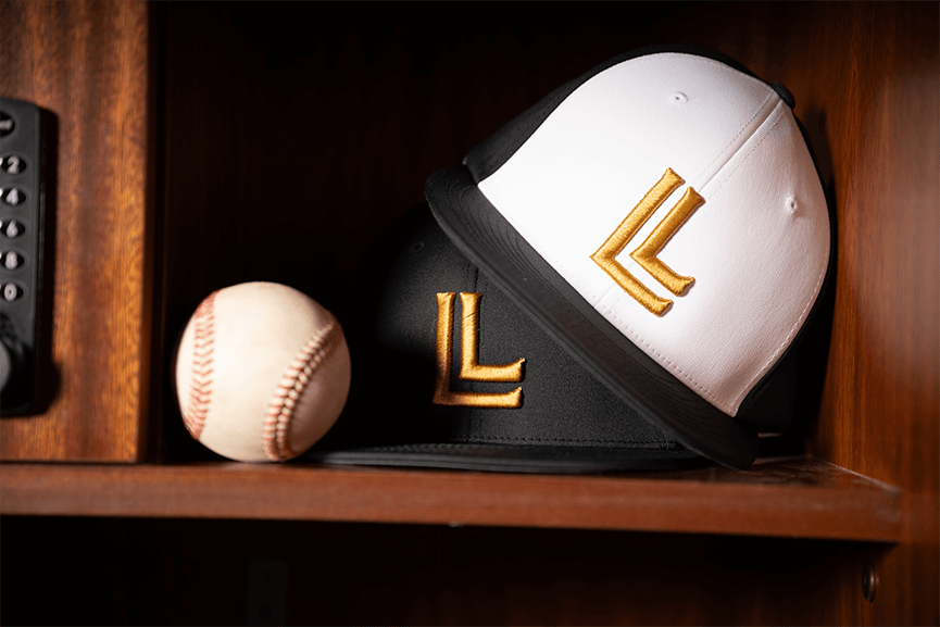 An image of two Luccini hats sitting on a shelf next to a baseball.